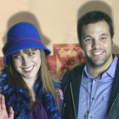 Smiling brunette woman in a blue hat, waving, alongside a smiling man with dark hair and scruffy facial hair